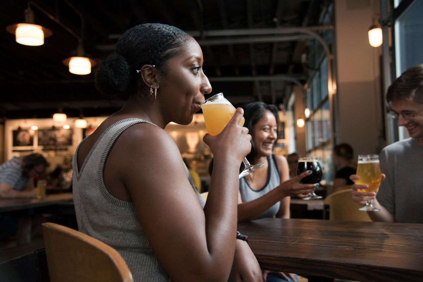 A woman enjoying a drink at a sociable bar table
