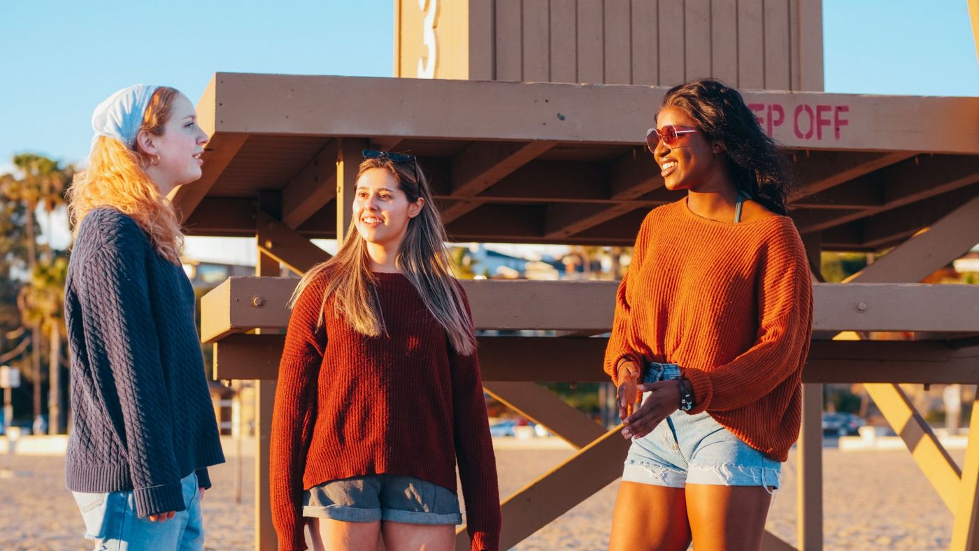 Three friends chatting in the evening sun on a beach
